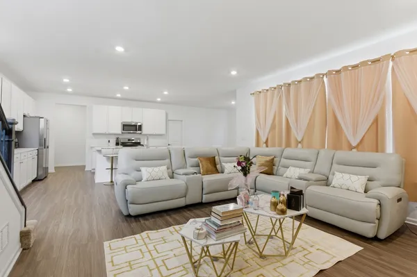 a kitchen with a sink dishwasher a refrigerator and white cabinets with wooden floor
