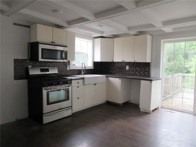 a kitchen with stainless steel appliances granite countertop a stove a sink and a microwave