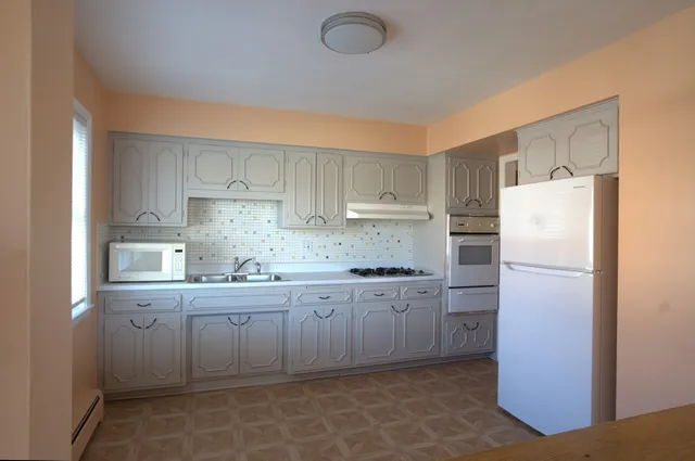 a kitchen with a sink a refrigerator and cabinets