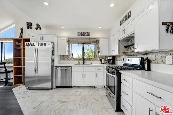 a kitchen with stainless steel appliances granite countertop a refrigerator a stove and a sink