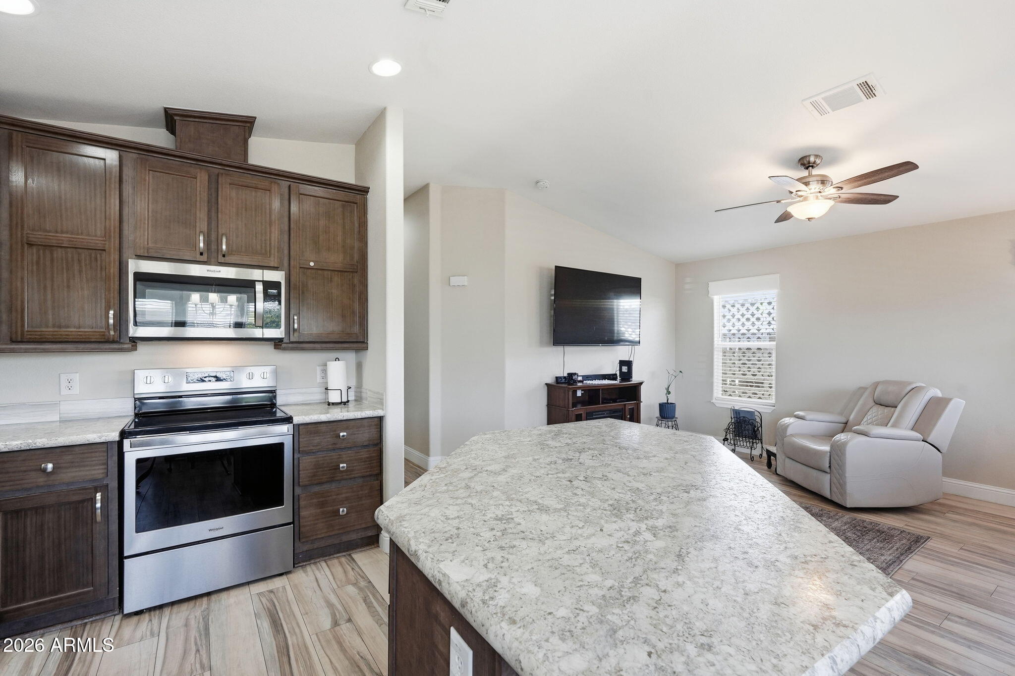 8865 East Baseline Road, Unit 1417 Mesa, AZ 85209 - Photo 15 of 47 a kitchen with stainless steel appliances granite countertop a stove top oven a sink dishwasher a dining table and chairs with wooden floor