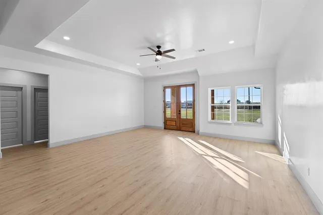 a view of an empty room with a window and wooden floor