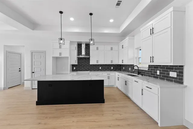 a large kitchen with stainless steel appliances granite countertop a large counter top a stove a sink and a refrigerator