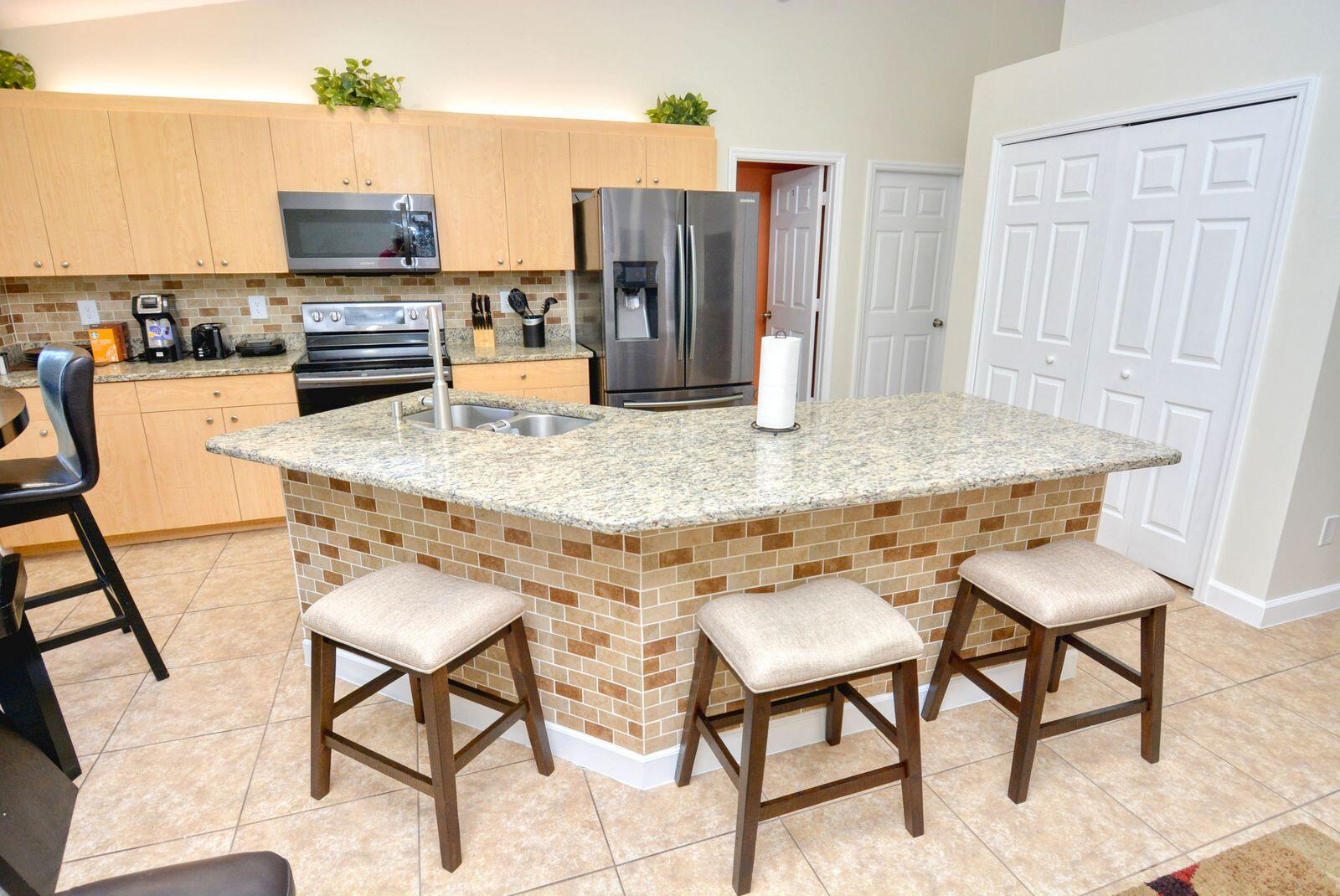 220 West Arbor Avenue Port St. Lucie, FL 34952 - Photo 10 of 32 a kitchen with stainless steel appliances kitchen island granite countertop a table chairs and a refrigerator