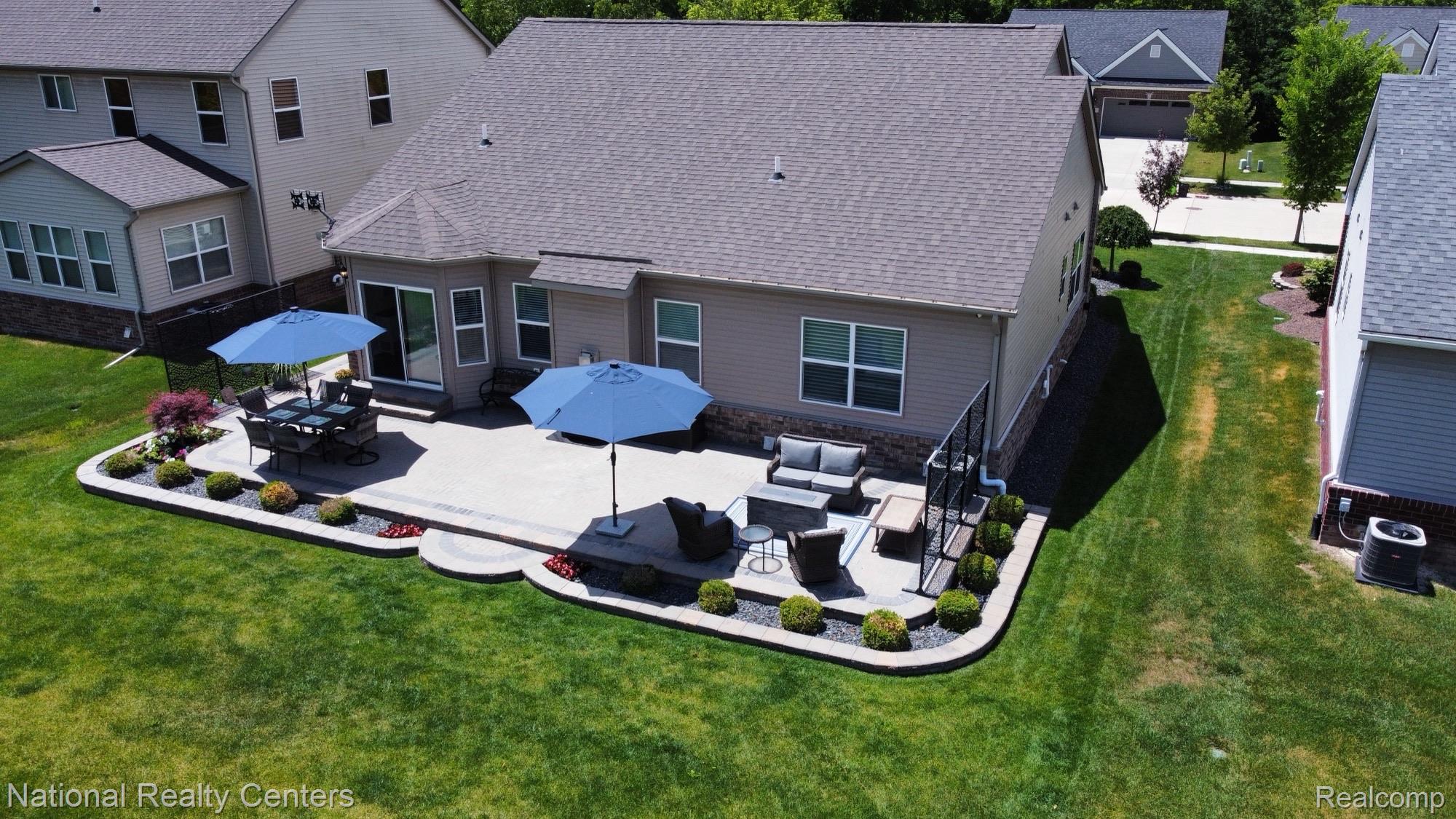 740 North Mill Street South Lyon, MI 48178 - Photo 3 of 56 Expansive rear patio featuring concrete surfacing, a built-in retaining wall with integrated landscaping, and a sliding glass door entry