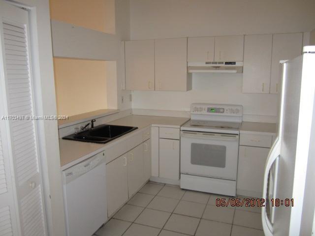 20820 San Simeon Way, Unit 26G Miami, FL 33179 - Photo 5 of 6 a kitchen with white cabinets and white appliances