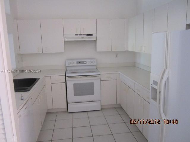 20820 San Simeon Way, Unit 26G Miami, FL 33179 - Photo 6 of 6 a kitchen with white cabinets and white appliances