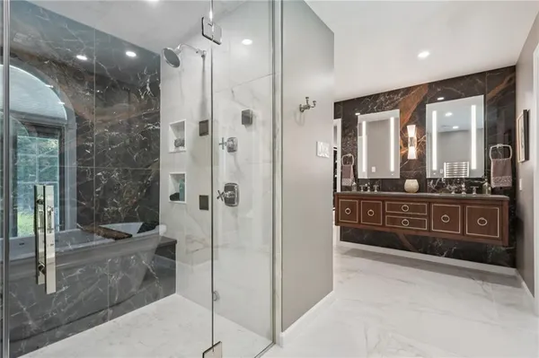 a bathroom with a mirror a double vanity sink and glass door