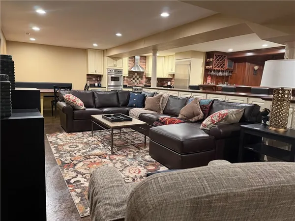 a living room with furniture kitchen view and a wooden floor