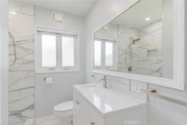 a bathroom with a sink toilet vanity and shower