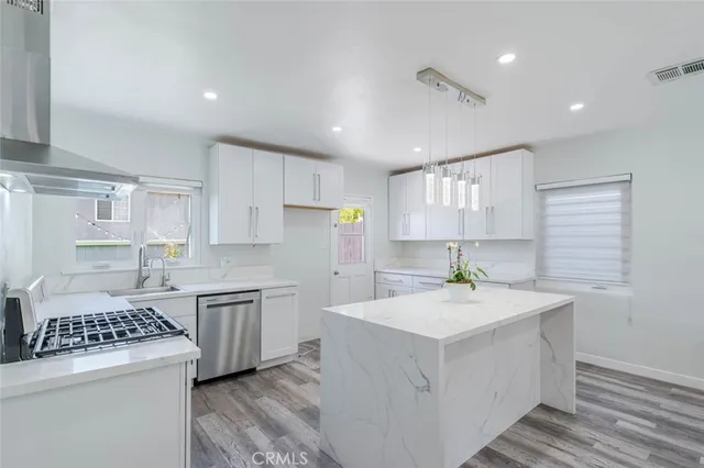 a kitchen that has a sink a stove and white cabinets