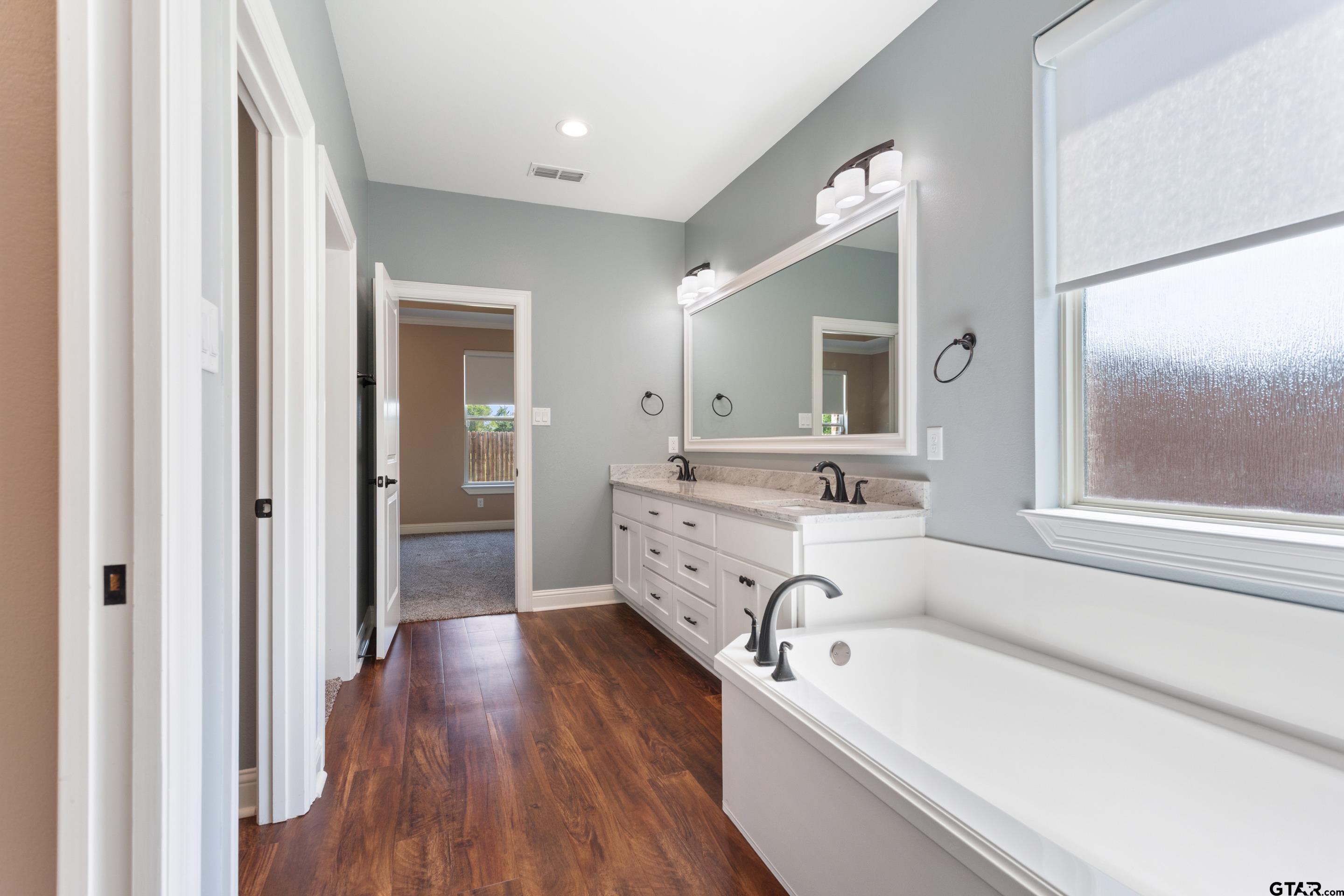 105 Nathan Road Chandler, TX 75758 - Photo 18 of 36 a bathroom with a tub a sink and a large mirror