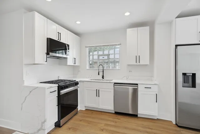 a kitchen with stainless steel appliances a sink cabinets and a wooden floor