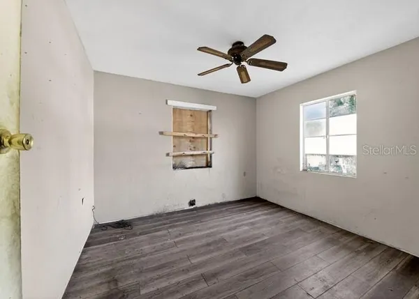 a view of empty room with wooden floor and fan