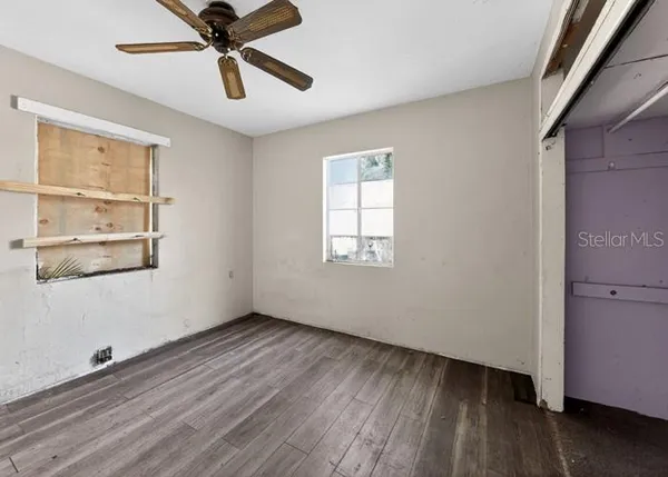 a view of an empty room with wooden floor and a window