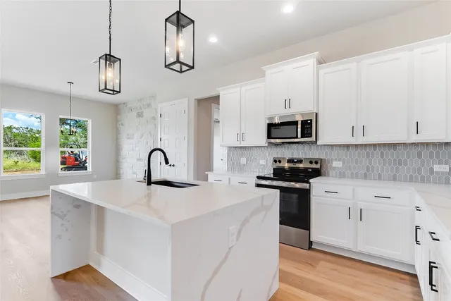 a kitchen with stainless steel appliances granite countertop a sink a stove and a refrigerator