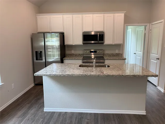 a kitchen with kitchen island granite countertop a stove a sink and a refrigerator