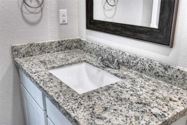 a bathroom with a granite countertop sink and a mirror