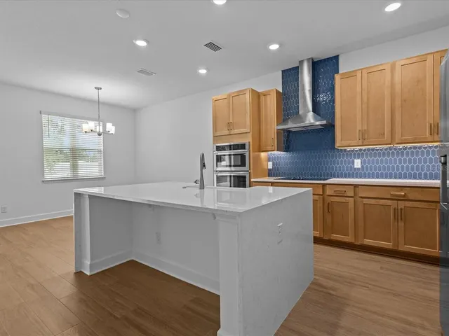 a kitchen with stainless steel appliances granite countertop a sink a stove a refrigerator cabinets and wooden floor