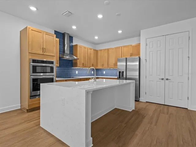 a kitchen with stainless steel appliances granite countertop a refrigerator a sink dishwasher and a stove with wooden floor