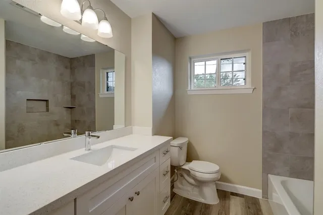 a bathroom with a toilet a sink a mirror and a window