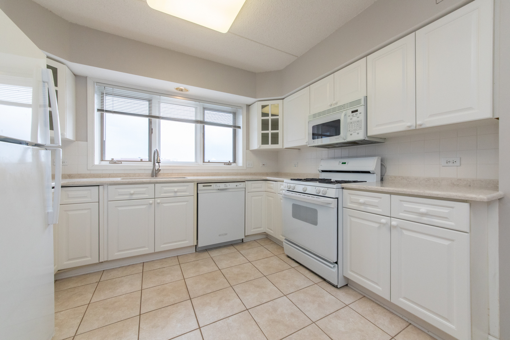 650 South River Road, Unit 601 Des Plaines, IL 60016 - Photo 10 of 20 a kitchen with white cabinets appliances a sink and a window