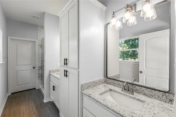 a bathroom with a granite countertop sink a mirror and a shower