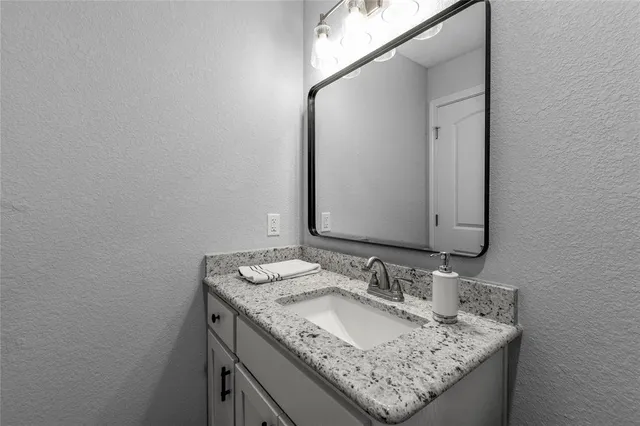a bathroom with a granite countertop sink and a mirror
