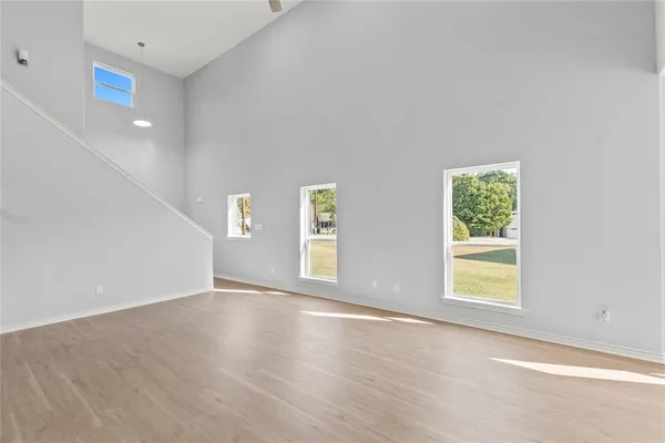 a view of an empty room with window and wooden floor