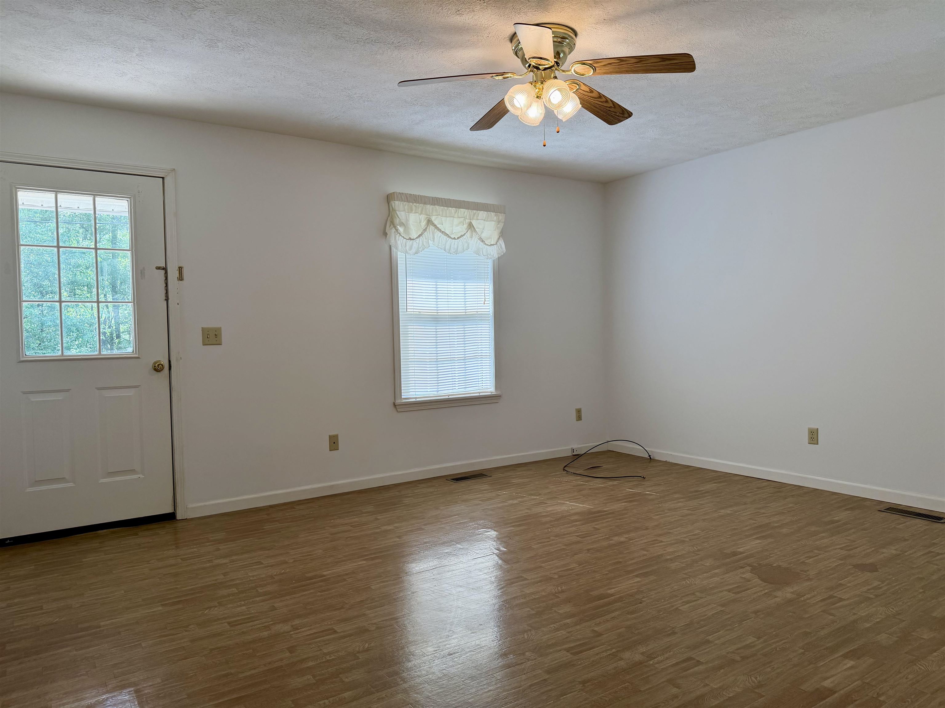 3010 Powell Chapel Road Middleton, TN 38052 - Photo 11 of 28 an empty room with wooden floor chandelier fan and windows