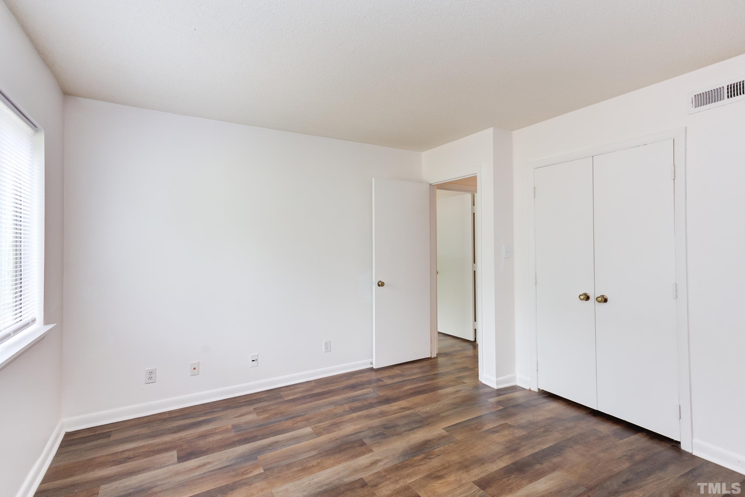 5060 Flint Ridge Place, Unit 5060 Raleigh, NC 27609 - Photo 14 of 29 a view of an empty room with wooden floor and a window