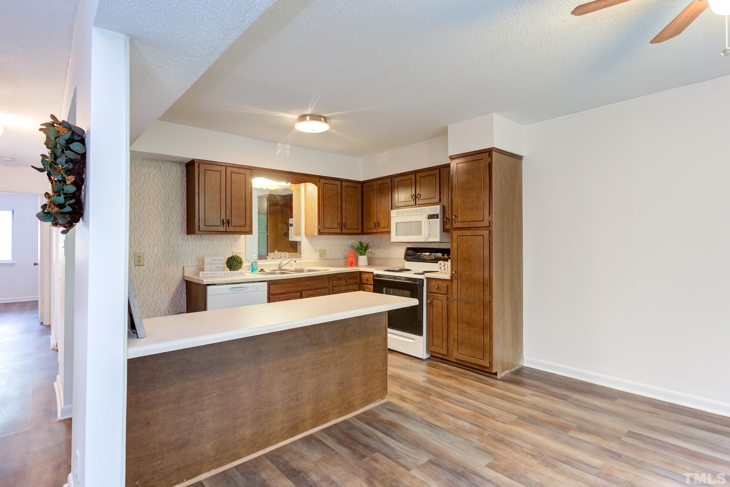 5060 Flint Ridge Place, Unit 5060 Raleigh, NC 27609 - Photo 10 of 29 a large white kitchen with a refrigerator a stove top oven a sink and dishwasher