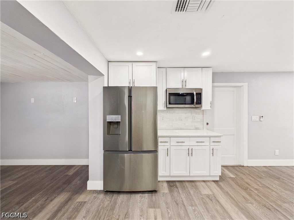 567 13th Street North Naples, FL 34102 - Photo 4 of 23 a kitchen with wooden floors white cabinets and stainless steel appliances