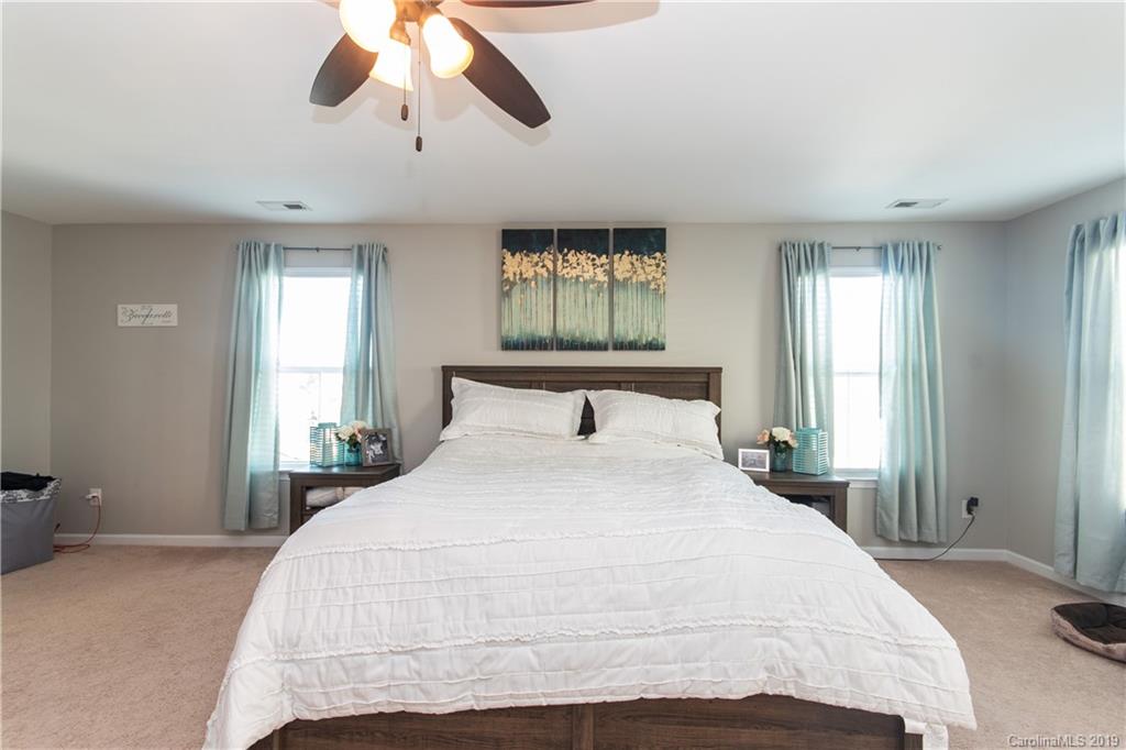 10937 Tailwater Street Davidson, NC 28036 - Photo 15 of 34 a bedroom with a large bed and a chandelier