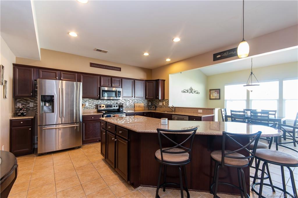 10937 Tailwater Street Davidson, NC 28036 - Photo 6 of 34 a kitchen with stainless steel appliances granite countertop a table chairs sink and cabinets