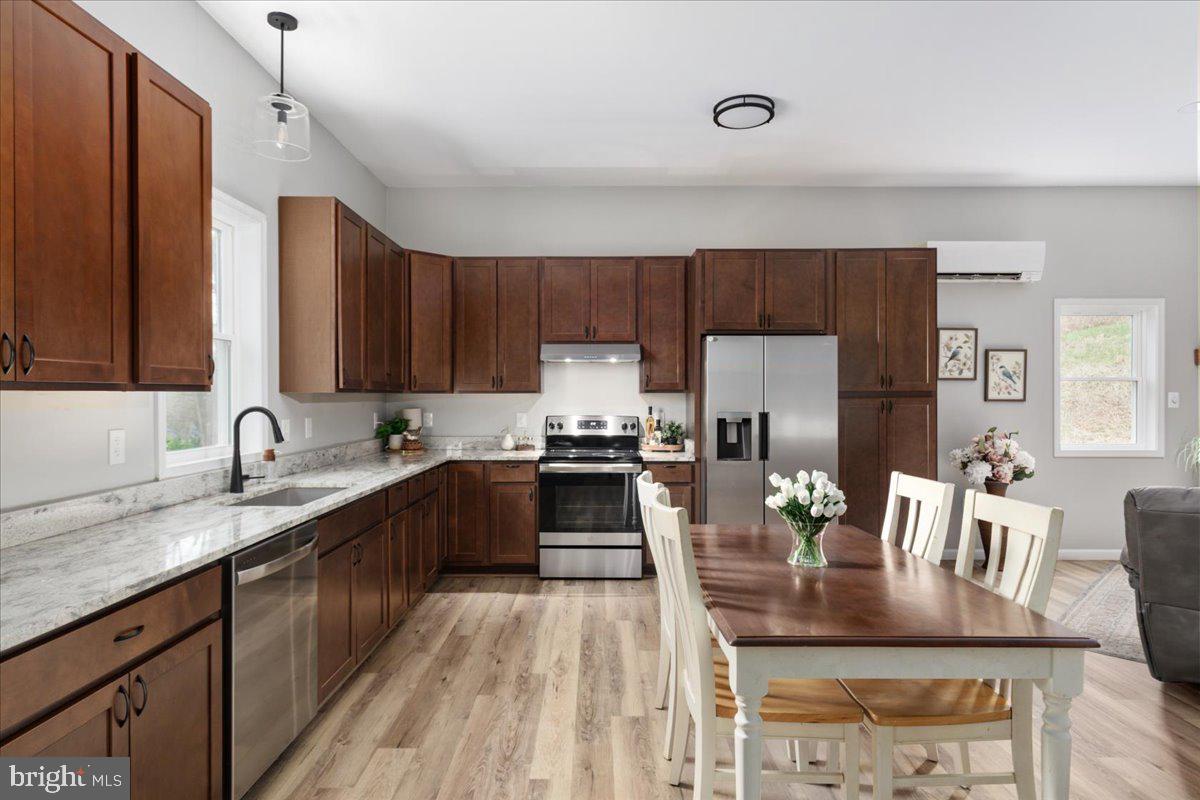 a kitchen with kitchen island granite countertop a stove a sink a refrigerator and wooden cabinets with wooden floor