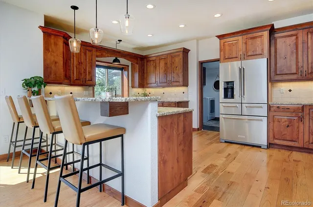 a kitchen with stainless steel appliances kitchen island granite countertop a table chairs and a refrigerator