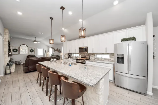 a kitchen with stainless steel appliances granite countertop a sink a stove a refrigerator and island with wooden floor