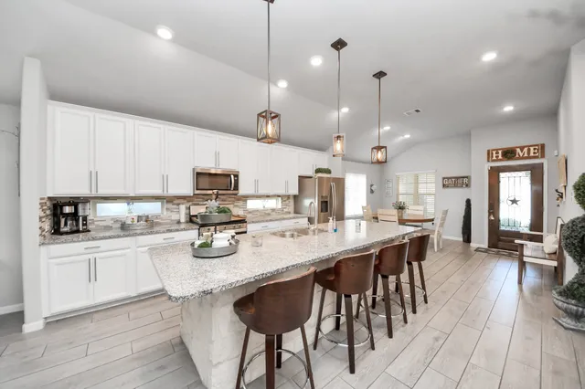 a kitchen with stainless steel appliances kitchen island granite countertop a stove a sink and a refrigerator