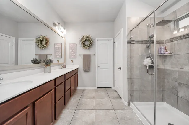 a spacious bathroom with a double vanity sink a mirror and a shower