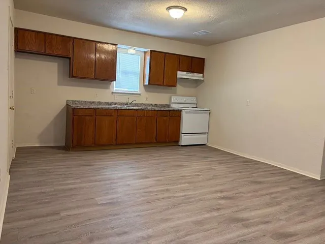 a kitchen with stainless steel appliances granite countertop a sink a stove and a wooden floors
