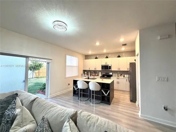 a kitchen with kitchen island granite countertop wooden floors and white cabinets