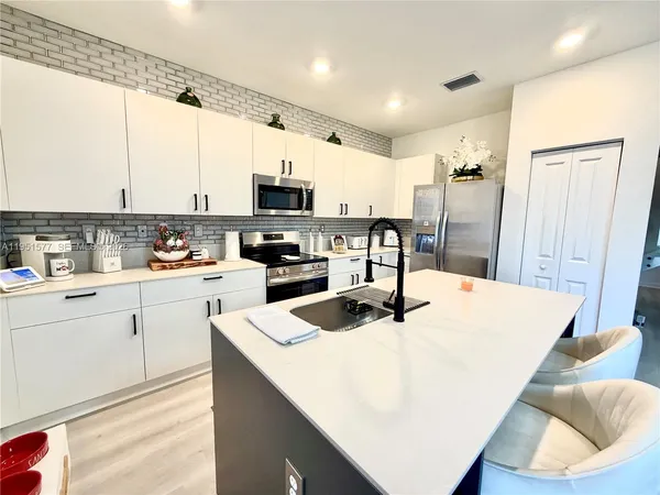 a kitchen with a dining table chairs and a refrigerator