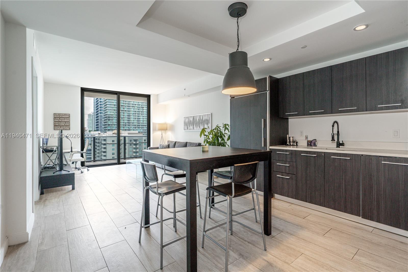 45 Southwest 9th Street, Unit 1205 Miami, FL 33130 - Photo 9 of 27 a kitchen with stainless steel appliances a dining table chairs and wooden floor