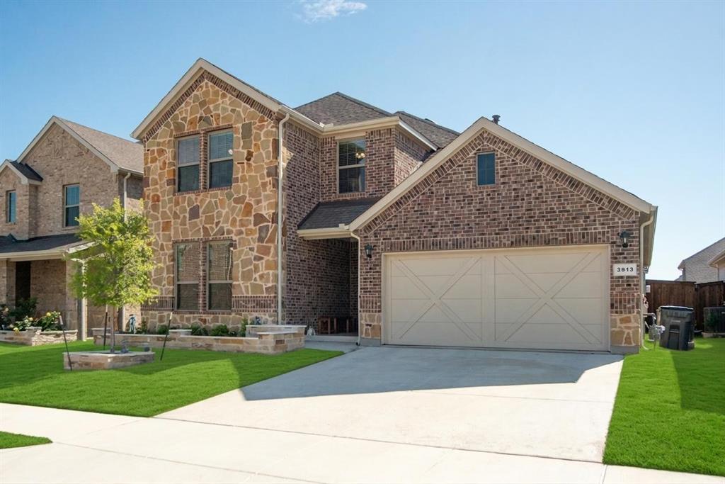 3813 Oldham Road Little Elm, TX 75068 - Photo 27 of 27 View of front of house featuring stone siding, a front lawn, driveway, an attached garage, and brick siding