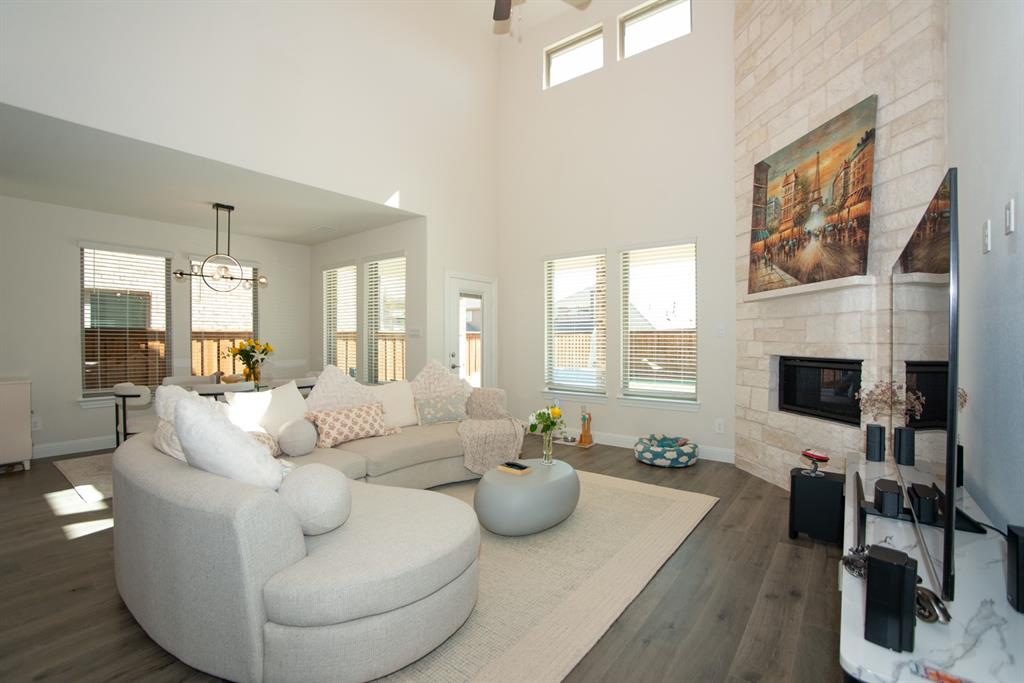 3813 Oldham Road Little Elm, TX 75068 - Photo 5 of 27 Living room with a fireplace, wood finished floors, a high ceiling, a ceiling fan, and a chandelier