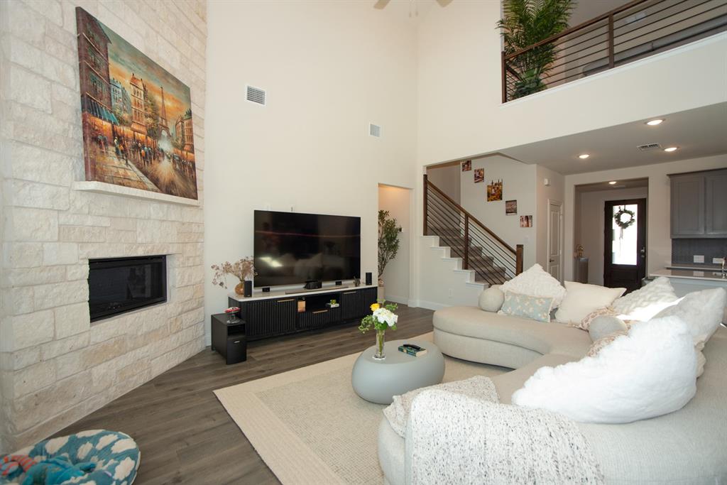 3813 Oldham Road Little Elm, TX 75068 - Photo 7 of 27 Living room featuring dark wood-style flooring, a stone fireplace, a high ceiling, a ceiling fan, and recessed lighting