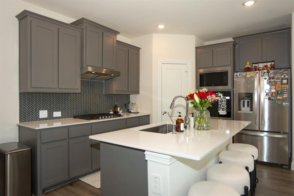 3813 Oldham Road Little Elm, TX 75068 - Photo 8 of 27 Kitchen featuring a kitchen breakfast bar, dark wood-style flooring, an island with sink, gray cabinetry, and decorative backsplash