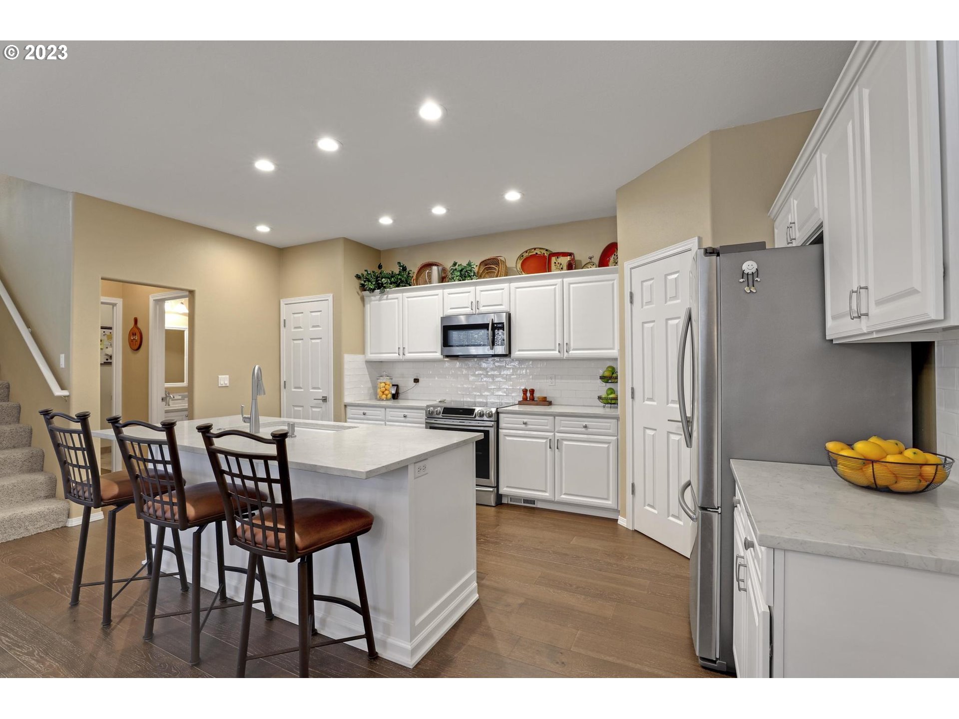 10698 Southwest Washington Street Portland, OR 97225 - Photo 13 of 25 a kitchen with stainless steel appliances a refrigerator a stove a sink dishwasher and white cabinets with wooden floor