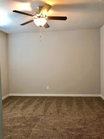 a view of a room with a ceiling fan and carpet
